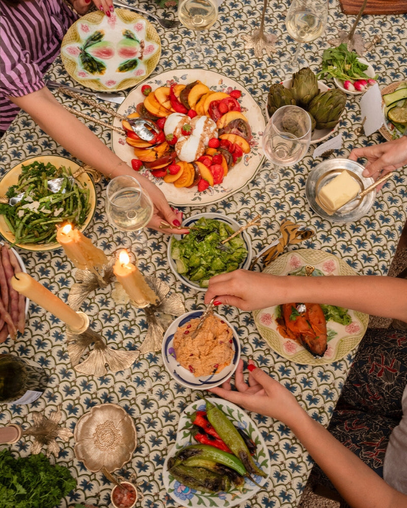 Sfeervolle mediterrane dinner party setting met zonovergoten tafel, tapas, wijn en kleurrijke tafeldecoratie