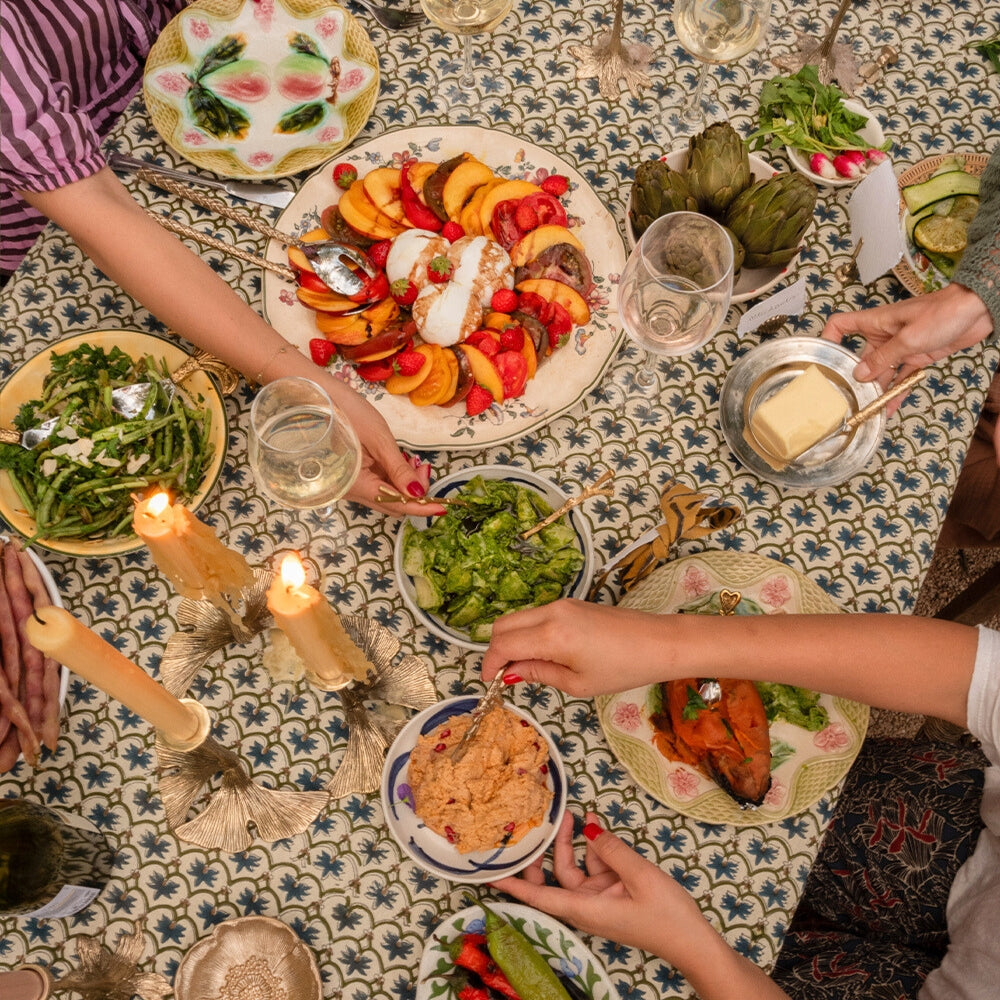 Sfeervolle mediterrane dinner party setting met zonovergoten tafel, tapas, wijn en kleurrijke tafeldecoratie