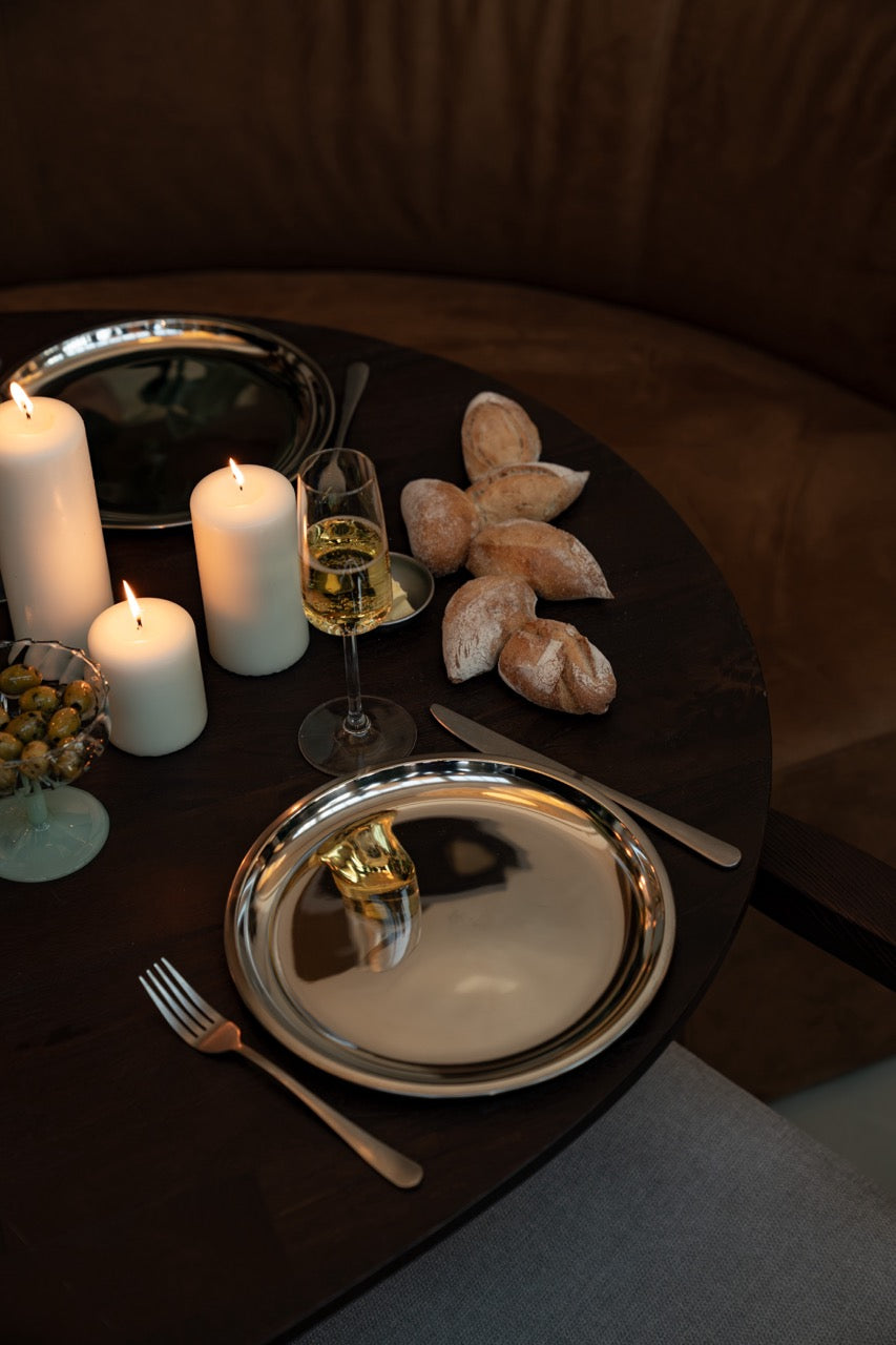 Flatlay van stainless steel borden in een serene tafelsetting met natuurlijke tinten en subtiele details – stijlvol, puur en uitnodigend.
