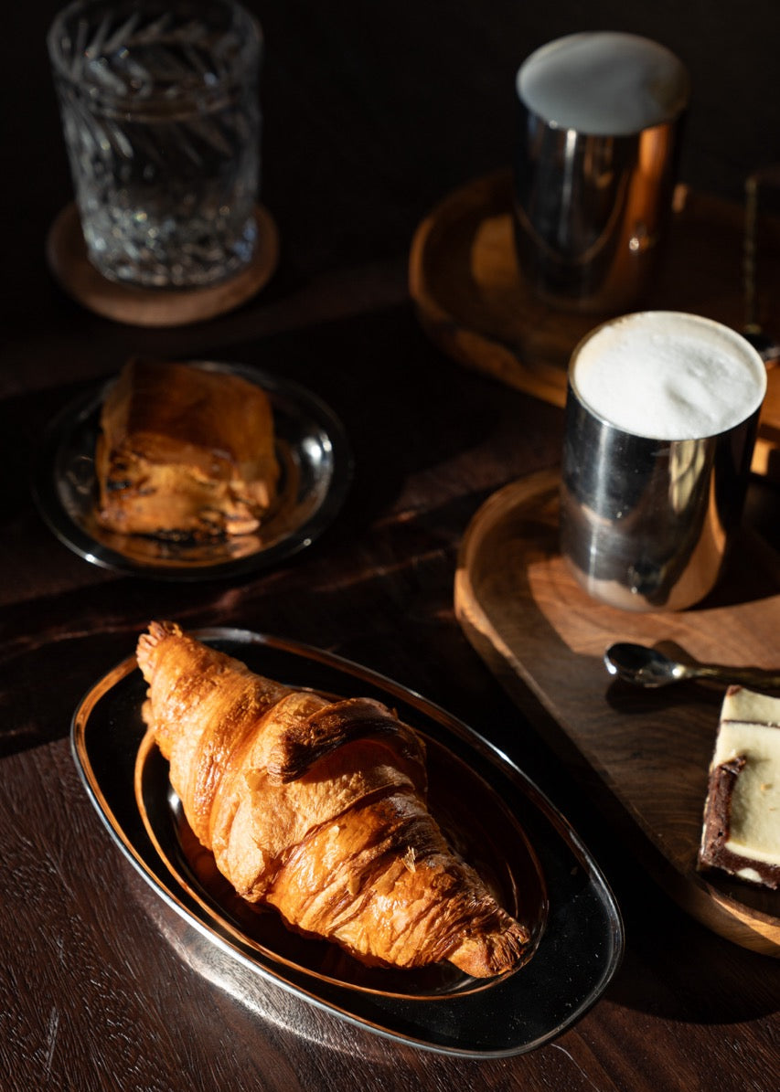 Warme, minimalistische tafelsetting met stainless steel servies – tijdloos design dat uitnodigt om samen te genieten.