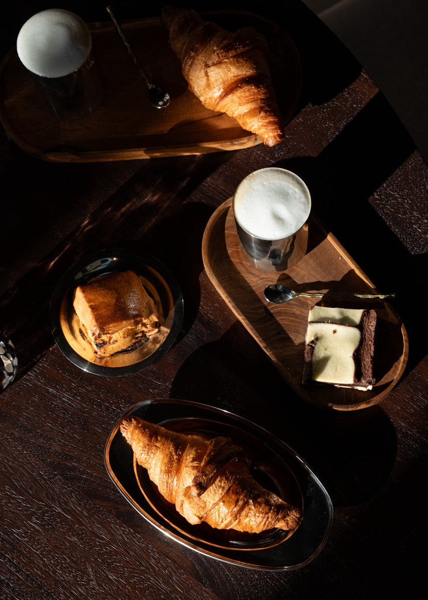 Flatlay van stainless steel servies in een warme setting met natuurlijke tinten – minimalistisch en stijlvol.