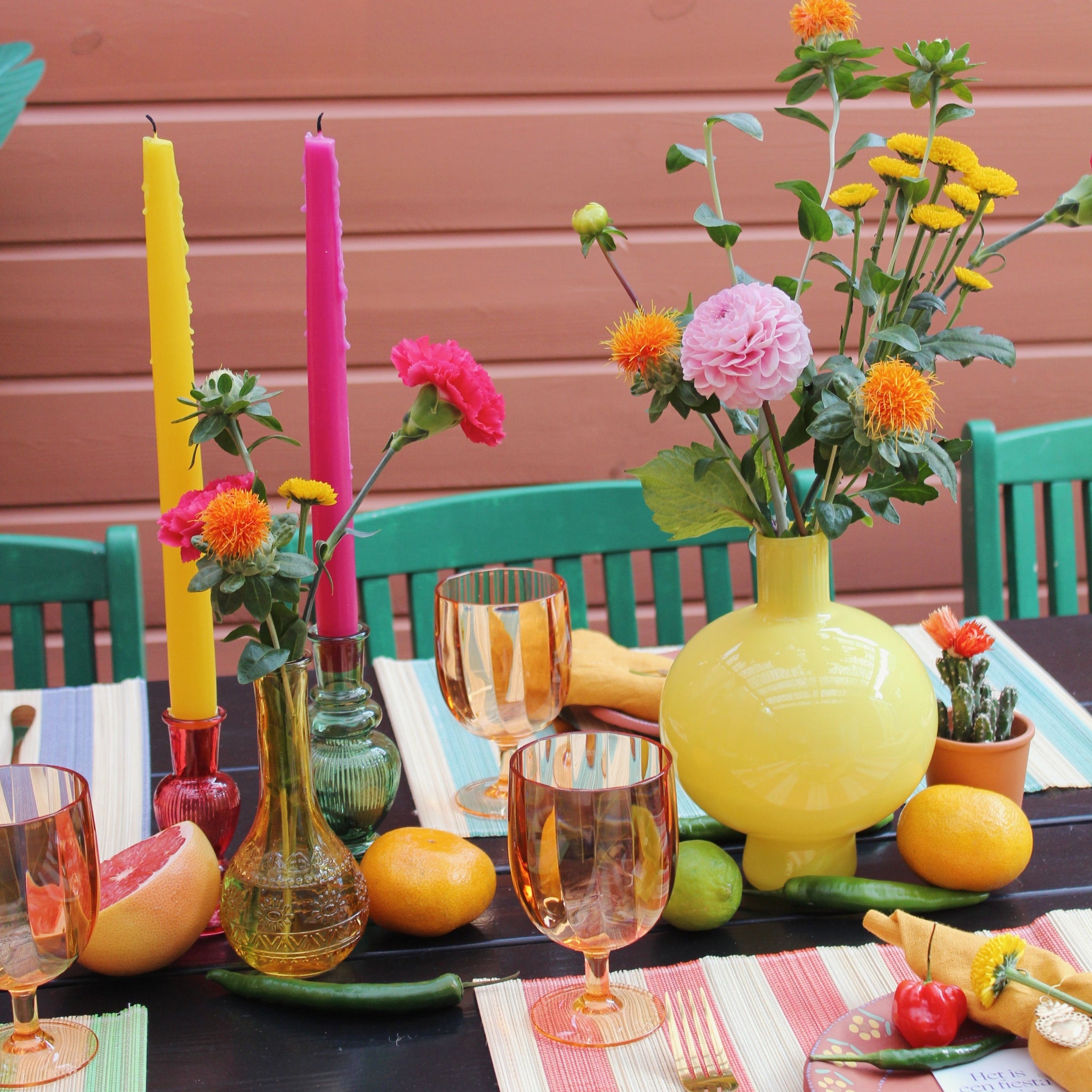 Zomerse tafelsetting met kleurrijke dinerkaarsen en tafeldecoratie.