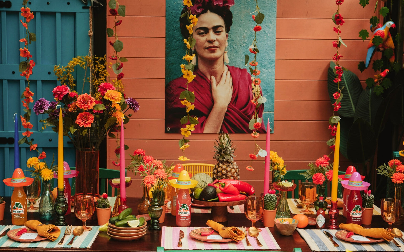 Kleurrijke Mexicaanse feesttafel geïnspireerd door Frida Kahlo, met levendige bloemen, traditionele decoraties en Jarritos drankjes, perfect voor een zomerse fiesta.