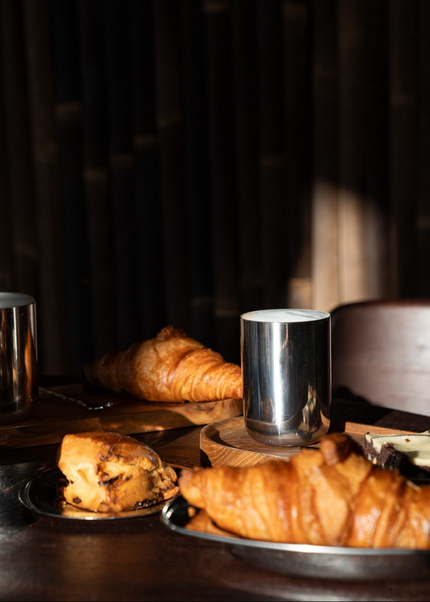 Warme, minimalistische tafelsetting met stainless steel servies – tijdloos design dat uitnodigt om samen te genieten.