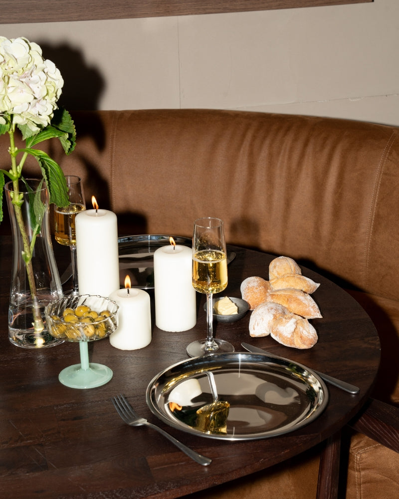 Sfeervol diner bij kaarslicht met roestvrijstalen details uit de Steel Your Table collectie – een moderne tafelsetting vol warmte en verfijning.