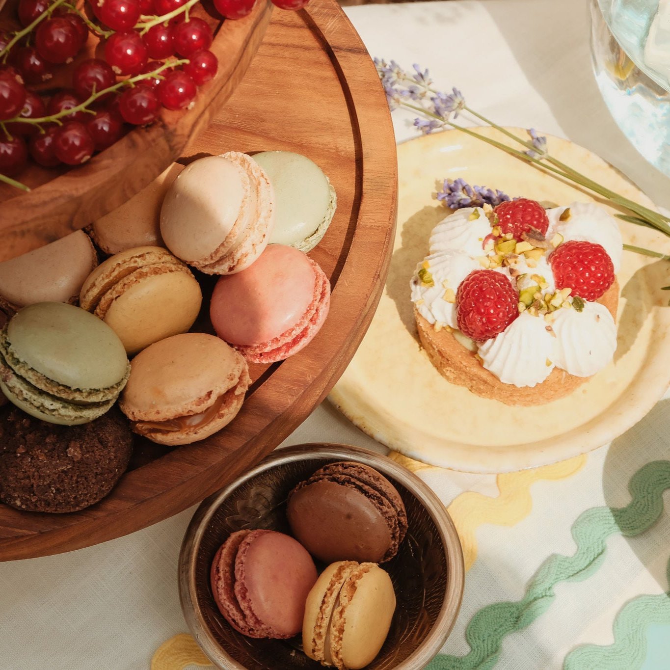 Luxe macarons en frambozengebak op houten serveerplank - Perfecte zoete traktaties voor elegante high tea's en feestelijke gelegenheden.